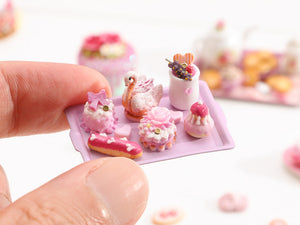 Beautiful presentation of pink miniature French pastries and treats (swan, éclair, religieuse)