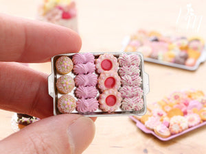 A hand for scale holding a miniature metal tray filled with handmade miniature food sweet treats including meringues in pink made from polymer clay