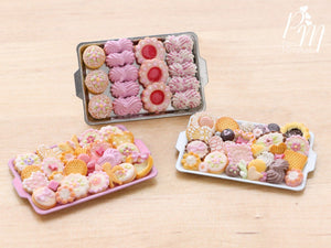 A collection of three miniature metal trays filled with handmade miniature food sweet treats including meringues and cookies made from polymer clay